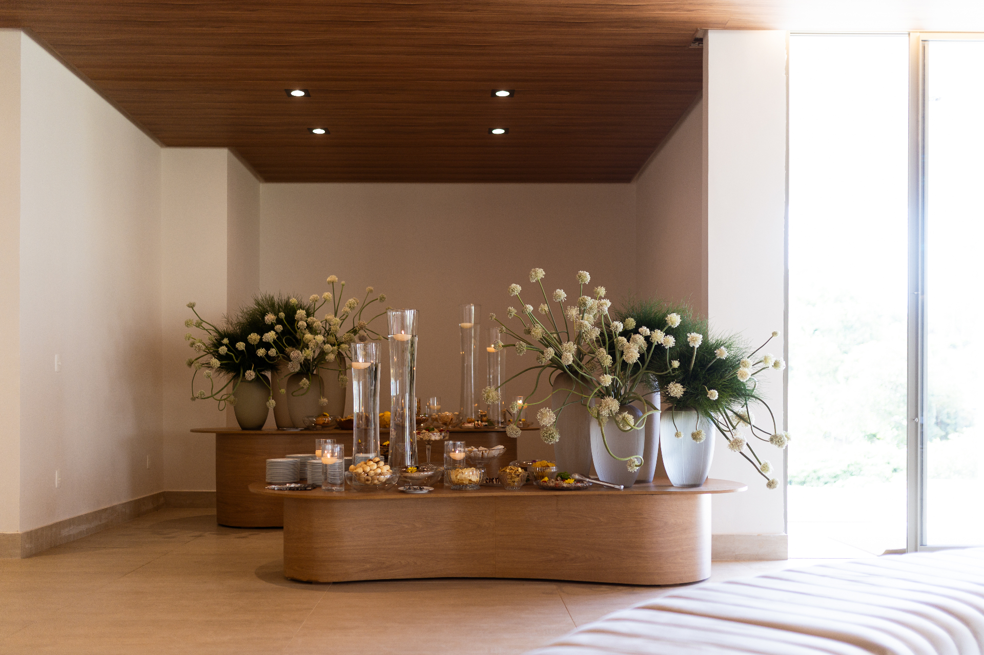 Mesa de apoio decorada no espaço Icon com flores, velas e iluminação natural.